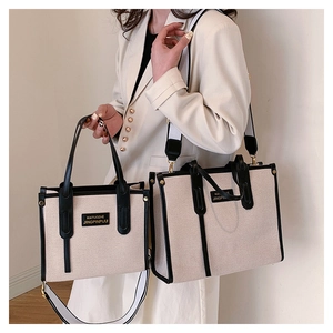 Detail of canvas tote bags in two sizes with black leather trim and striped shoulder strap