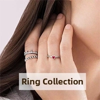 Close-up of stacked silver rings with red heart gemstone and crown micro-pave details