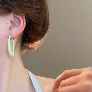 Close-up of minimalist light green round hoop earring on model with glossy finish