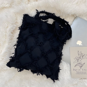 Close-up of black fringe diamond texture on canvas tote bag with laptop and plush background