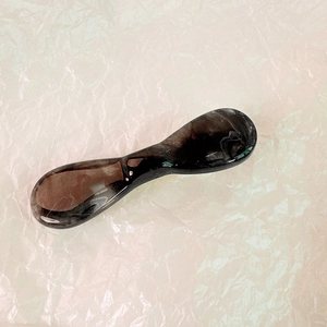 Détail de la texture marbrée et de la finition polie de la pince à cheveux noeud écaillé