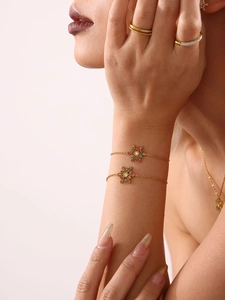 Detail eines goldenen Schneeflocken-Armbands mit bunten Zirkonsteinen am Handgelenk