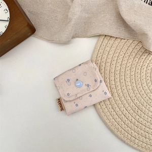 Detailed view of floral cotton pouch with blue button closure and brand label