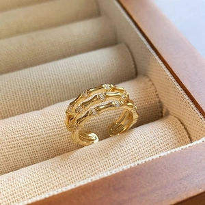 Détail de la bague dorée texture bambou et zircons sur doublure en tissu beige