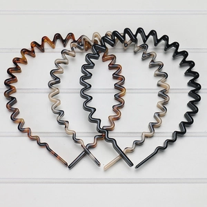 Close-up of four wavy acetate hairbands in tortoiseshell, beige, and black colors