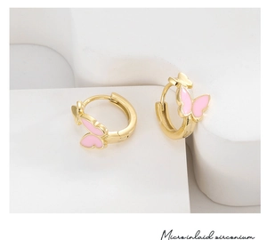 Macro shot of gold butterfly earrings with pink enamel inlay and micro-set zirconia