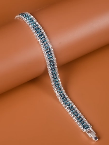 Detailed view of silver bracelet featuring blue and white crystals on a smooth surface