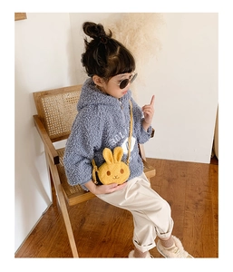 Detail of a cute yellow plush bunny crossbody bag worn with a blue fleece hoodie for kids