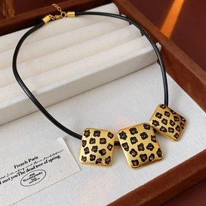 Detail of leopard print square pendants with amber rhinestones on a black cord necklace