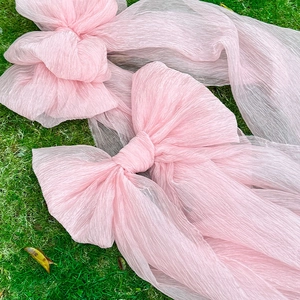 Pink pleated tulle bow decoration for outdoor wedding events and parties on green lawn