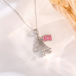 Detailed close-up of fashion necklace featuring camera, Eiffel Tower and glasses charms