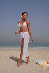 Detail of white three-piece bikini set with gold ring and high slit mesh beach skirt