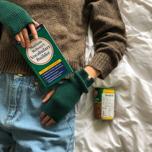 Detalle de guantes de punto acanalado verde oscuro con diseño sin dedos y textura