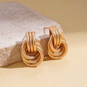 Close-up of golden multi-layer interlocking circular earrings on a textured stone