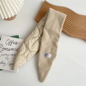 Detail of beige quilted scarf showing waffle texture and creative woven label