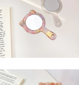 Detailed close-up of a cat-ear shaped acetate handheld mirror with marble pattern