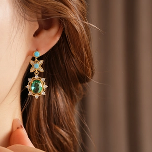 Détail de boucles d'oreilles vintage dorées avec pierres vertes et zircons