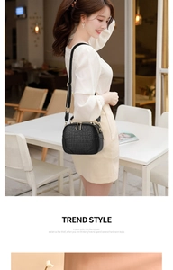 Detail of black crocodile texture bag with gold zipper and wide canvas shoulder strap
