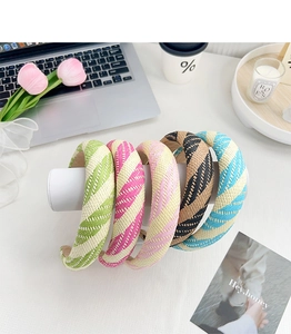 Assorted candy-colored braided headbands displayed on a stylish desk with home decor