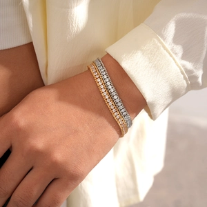 Close-up of stacked gold and silver chain bracelets with sparkling zircon stones