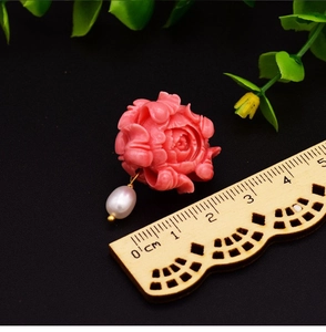 Macro shot of 925 silver pink floral earring with hanging natural baroque pearl