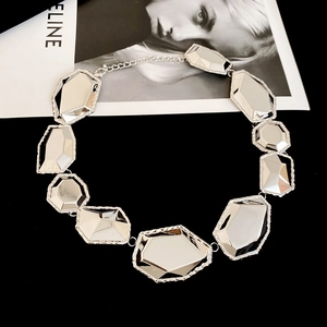 Vue détaillée d'un collier argenté géométrique avec blocs polis sur fond noir profond