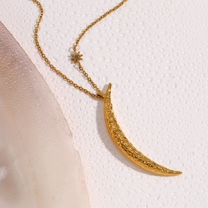 Detail of 18K gold-plated crescent moon pendant and star charm over water droplets