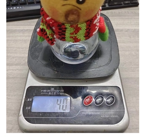 Detailed view of a Christmas candy jar with a plush toy lid on a digital scale