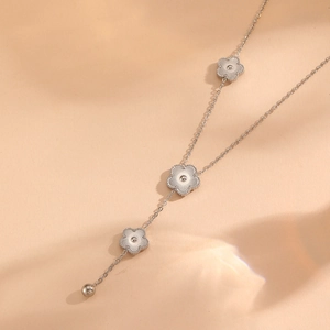Detail of silver clover pendant necklace with textured petals and steel bead tassel