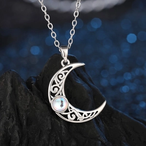 Exquisite silver crescent moon necklace with moonstone on a textured dark rock base