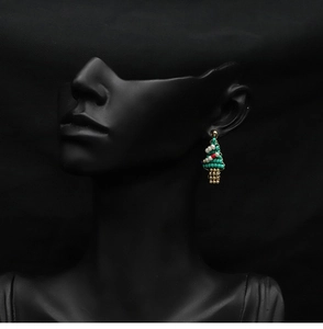 Macro detail of handmade Christmas tree beaded earrings with natural pearls on a model