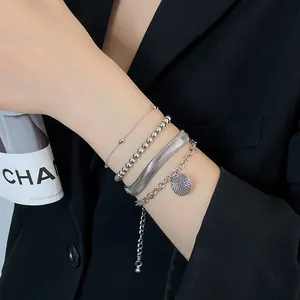 Dettaglio di un set di bracciali a strati in argento con catena snake e ciondolo tondo