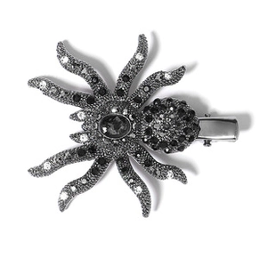 Detail of a spider-shaped hair clip with black and white crystals on a white background