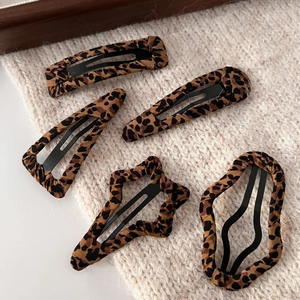Set of five diverse leopard print fabric-wrapped metal hair clips on a cozy knit fabric
