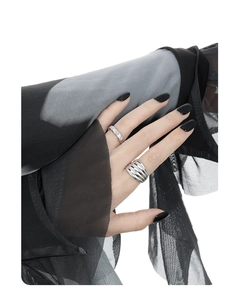 Detail of layered wavy silver rings on model hand with elegant matte metal texture
