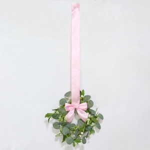 Close-up of artificial eucalyptus wreath with white berries and elegant pink silk bow