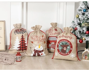 Kerstcadeauzakjes van jute met sneeuwpop en rendier print op een houten vloer