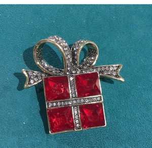 Detail of vintage gift box brooch with red crystals and white rhinestones on teal leather