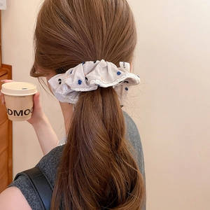 Detail of fabric scrunchie with lace trim and polka dots worn in a ponytail