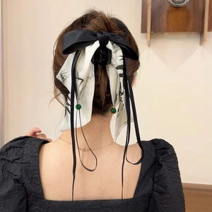 Détail d'une pince à cheveux avec nœud en soie style encre de chine et perles vertes