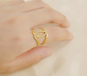 Close-up of golden interlocking C ring with twist texture on a hand model