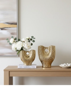 Détail de la texture martelée dorée sur des vases en céramique au design évidé moderne