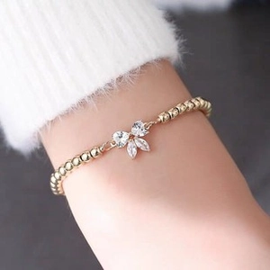 Close-up of golden adjustable wire bracelet with crystal bow charm on a model's wrist