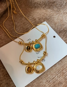 Détail de colliers en chaîne serpent plaqué or 18 carats avec pendentifs œil de tigre