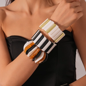 Three stacked bold acrylic geometric elastic bracelets in black, white, and gold colors