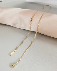 Close-up of golden stainless steel snake chain necklace with lobster clasp on silk