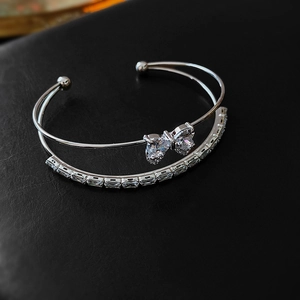 Macro shot of silver double-layered bangle with bow motif and sparkling zircon stones