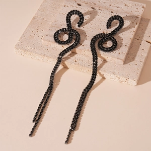 Detail view of black rhinestone twist earrings with long tassels on beige stone blocks