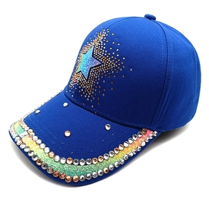 Close-up of sparkling rhinestones and colorful star patterns on a royal blue baseball cap