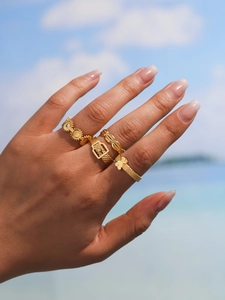 Dettaglio di quattro anelli geometrici vintage placcati in oro 18K indossati in spiaggia